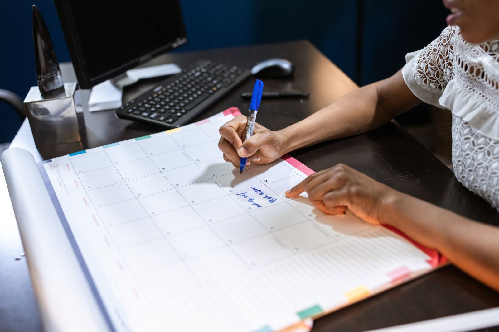 A person writing entries into a ruled ledger book at a desk