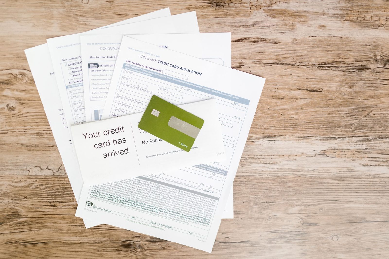 A credit card arrival letter and card lying on a scattered pile of documents
