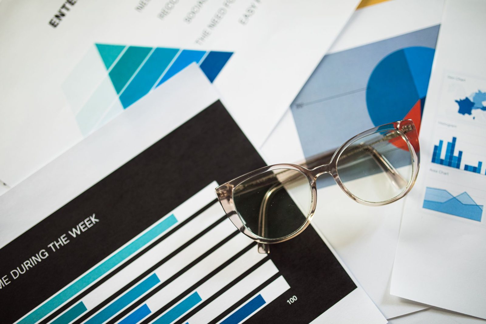 Printed bar charts and a pair of glasses on a desk