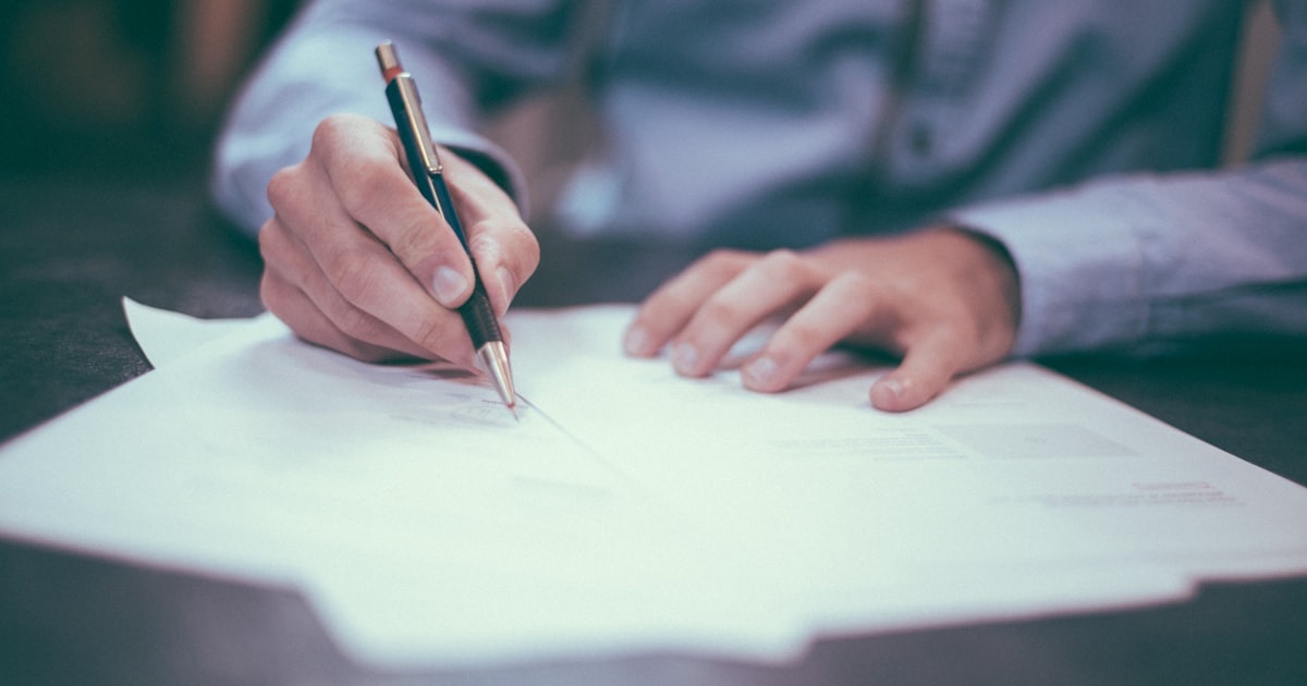 Professional signing financial documents at a desk