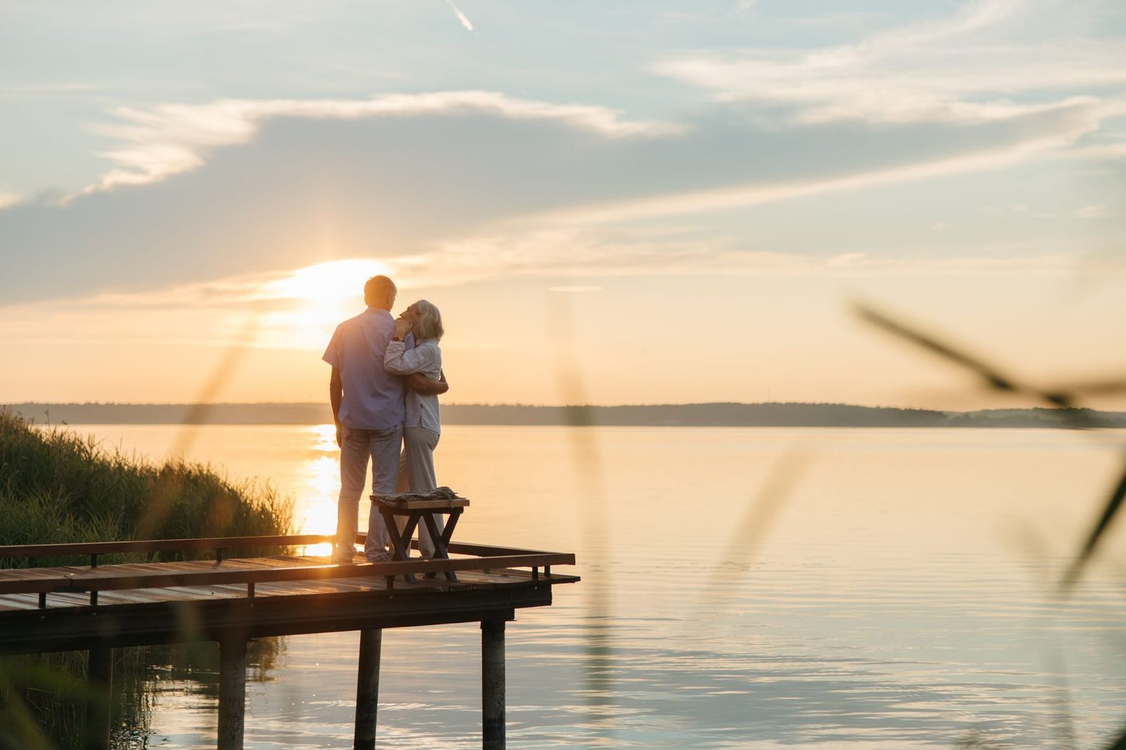 The silhouette of a couple standing at the end of a pier at sunset