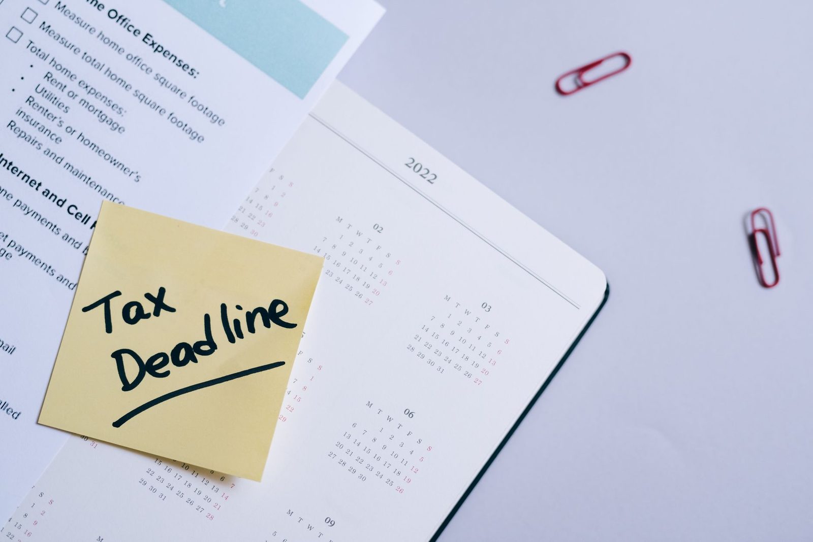 A sticky note reading tax deadline clipped to an open planner