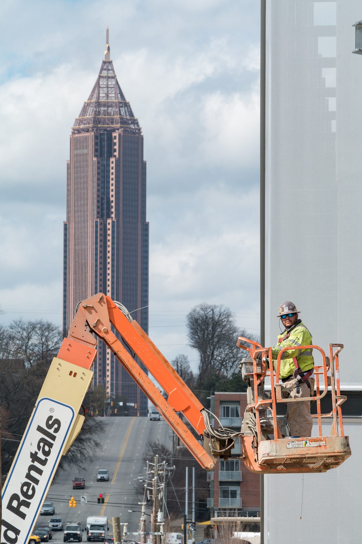 Construction worker finishing exterior facade work on a building under construction, illustrating the progress-billing cycle behind construction factoring
