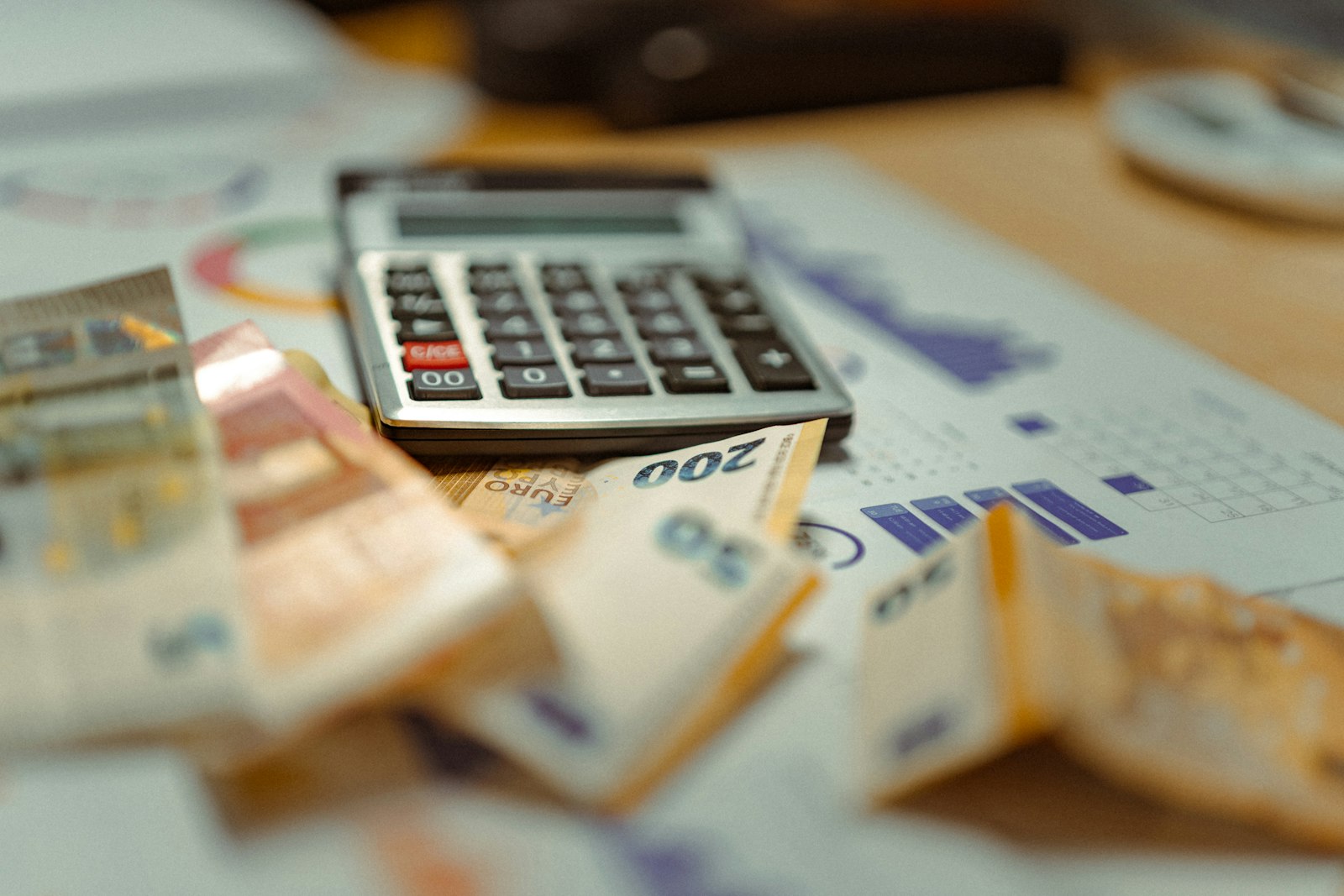 Calculator resting on a stack of cash, illustrating the arithmetic behind a factoring company's percentage fee