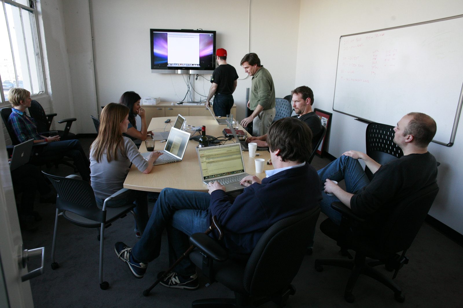 Team working around a conference table with laptops, representing the back-office invoicing and collections work a factoring company handles for its clients