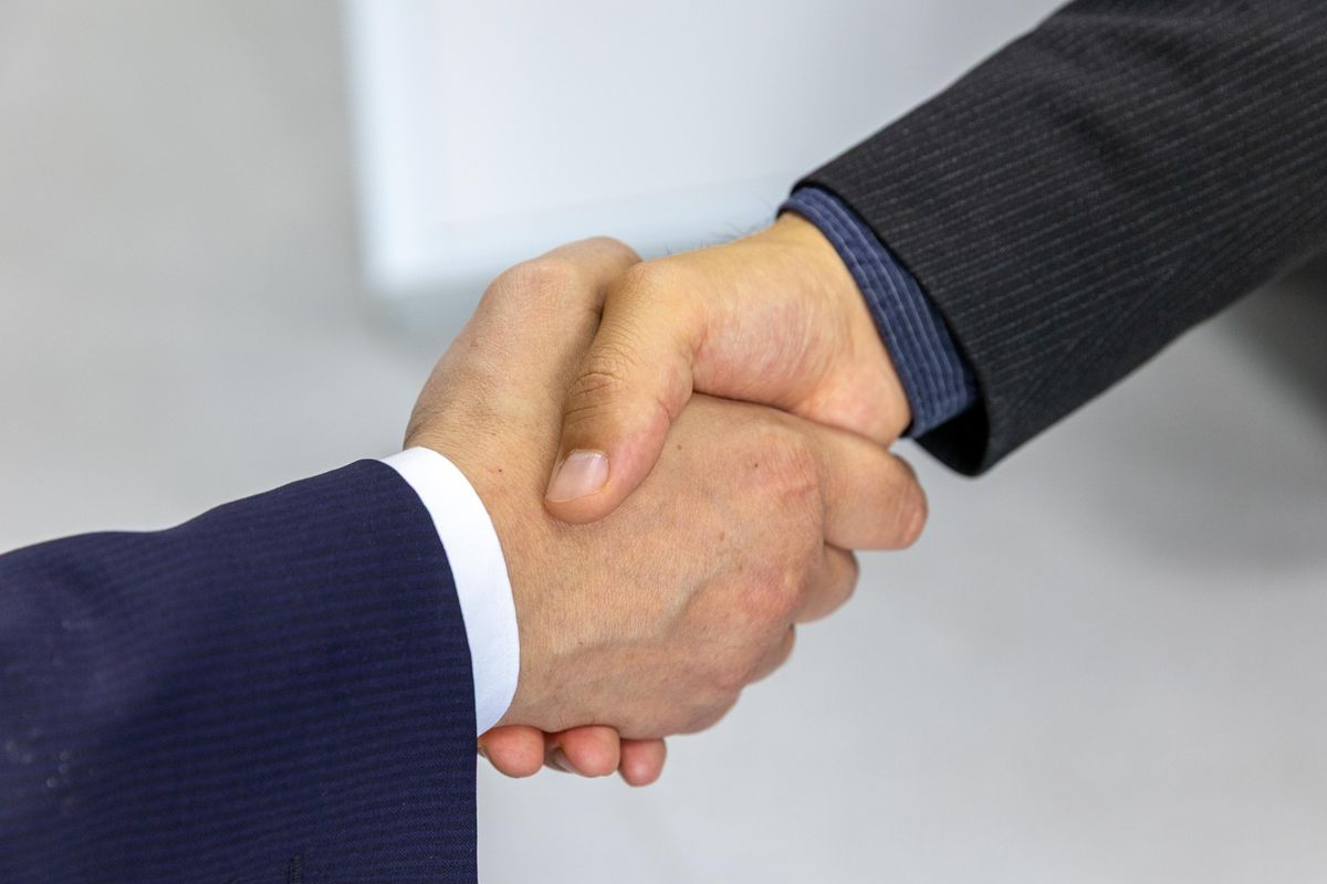 Two business professionals shaking hands after agreeing to the terms of a factoring contract