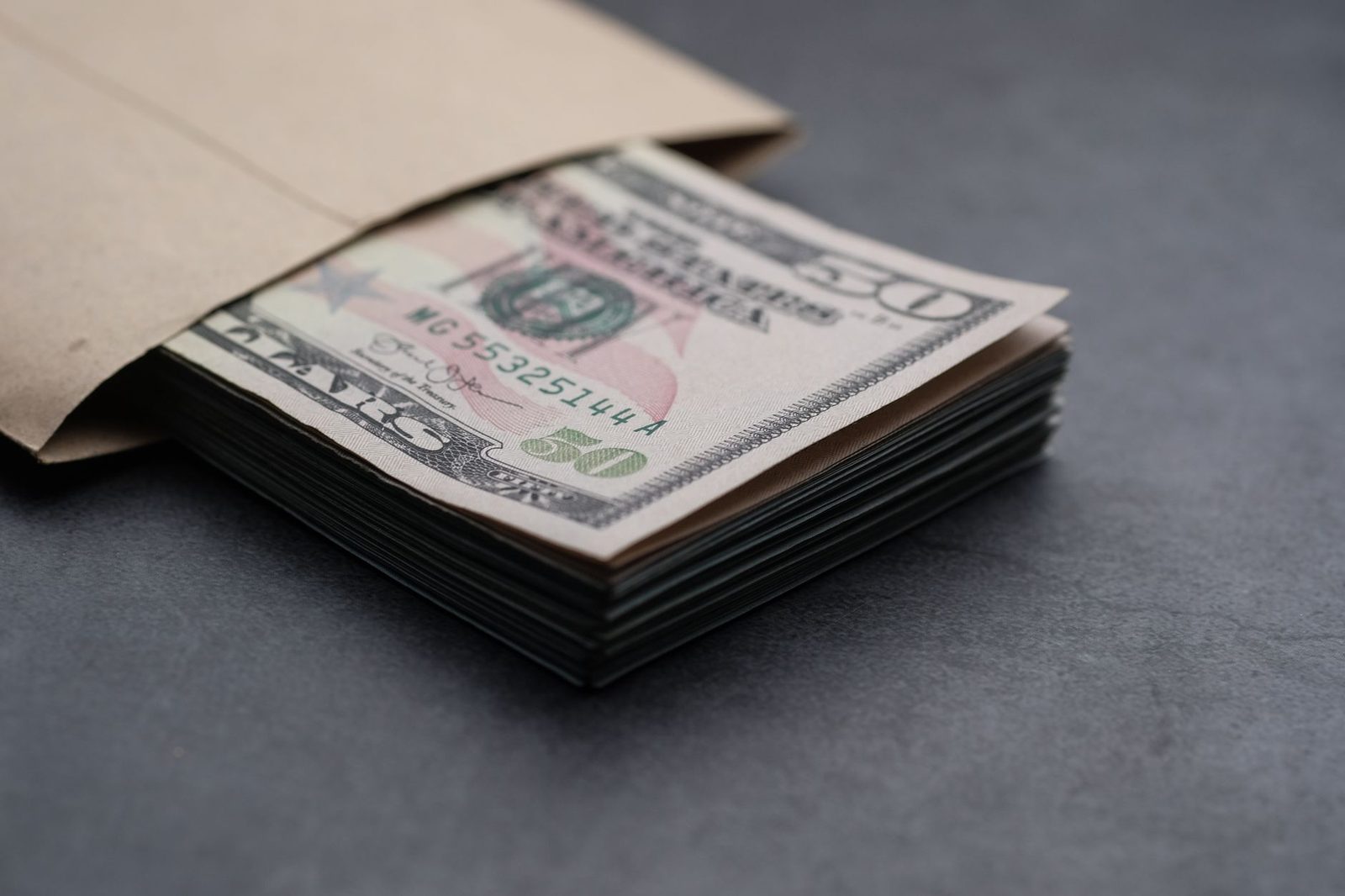 A stack of banknotes resting on a plain dark surface