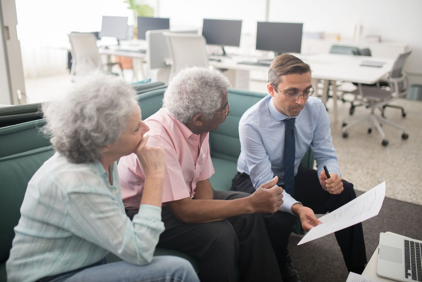 An adviser talking with two older clients in an office